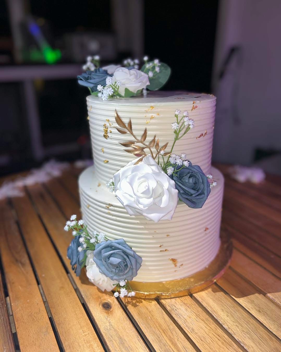 Two-tier white wedding cake with blue roses